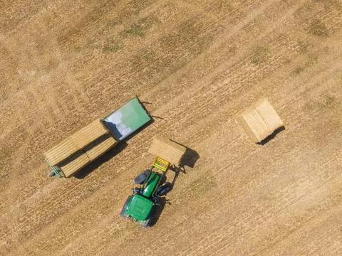 Top view of green tractor loading straw bales on a trailer. Stock Photos