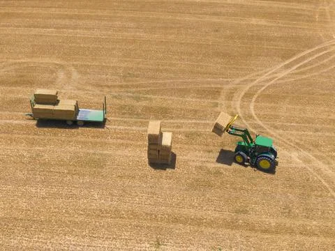 Top view of green tractor loading straw bales on a trailer. Stock Photos