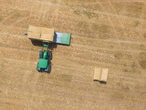 Top view of green tractor loading straw bales on a trailer. Stock Photos