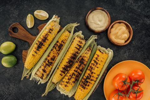 Top view of grilled corn covered in leaves on kitchen table Photos