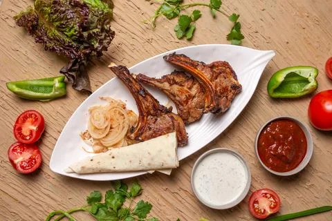 Top view Grilled lamb chops with vegetables and lavash bread on a wooden tabl Stock Photos