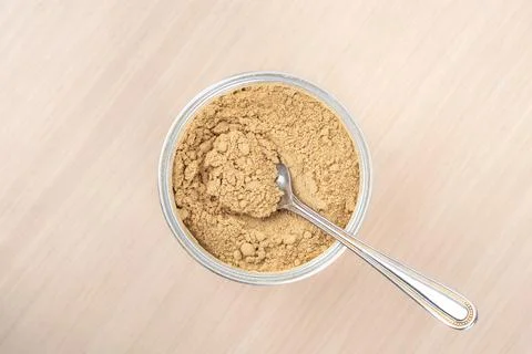 Top view of ground ginger root powder and a spoon in a jar. Stock Photos
