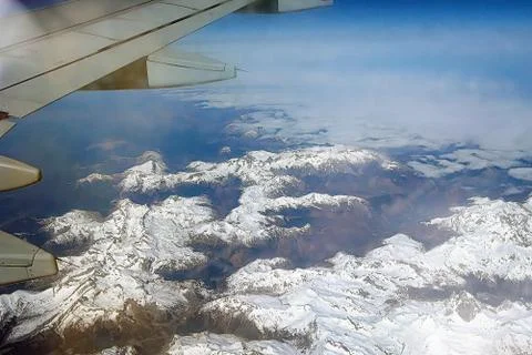 Top view of the ground from the plane. Mountain peaks of the Alps, covered wi Stock Photos