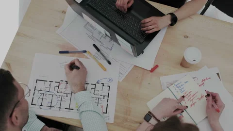 Top view. A group of young focused designers create plan of a contemporary multi Stock Footage 106202195