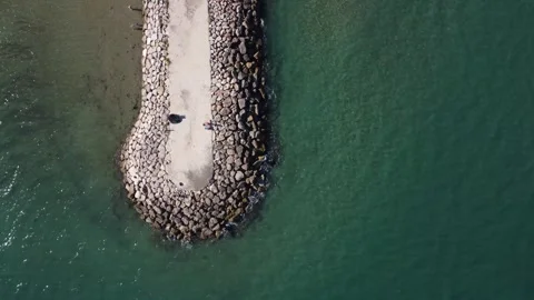 Top view of a groyne surrounded by rocks stretching into the sea Stock Footage 268614620