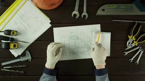 Top view of a guy writing down numbers from the schematics Stock Footage 80049323
