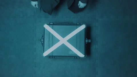 Top view of a hacker man wearing hood opening silver suitcase with a white cross Stock Footage 127745930