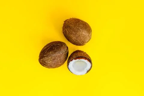 Top view half and two whole coconuts on a yellow background. Tropical summer Stock Photos