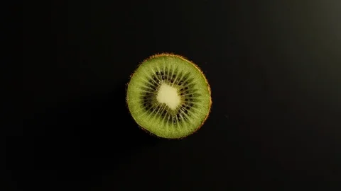 TOP VIEW: Half of a kiwi rotates on a black surface - Stop motion Stock Footage 100258225