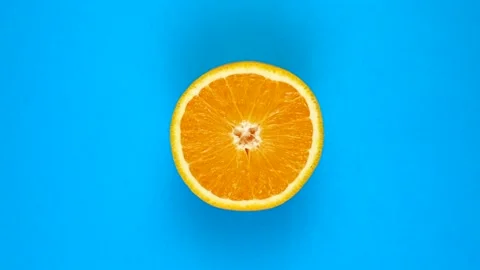 TOP VIEW: Half of an orange rotates on a blue surface - fast motion Stock Footage 166744852