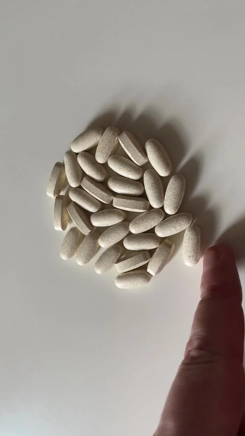 Top View of Hand Adjusting and Sweeping Away Vitamin Pills on White Background Stock Footage 340214538