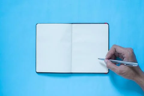 Top view of hand and notebook on blue and pinl pastel color bakcground Stock Photos
