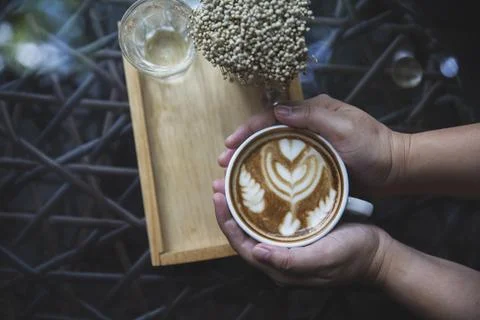 Top view hand with cup of coffee with hot latte art in cafe shop or restauran Foto stock