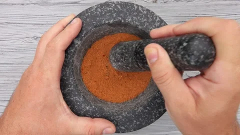 Top view of the hand with heavy pestle grinding mix of spices in the mortar Stock Footage 296691837
