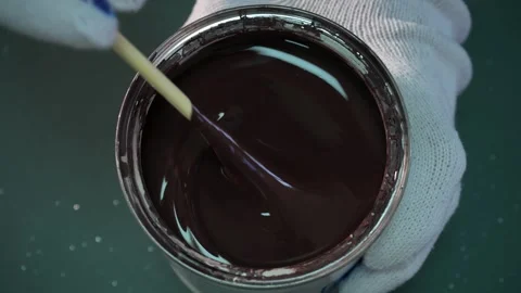 Top view of a hand holding a can of brown paint, stirring it with a stick Stock Footage 293953802