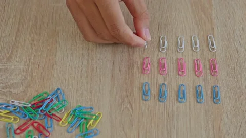 Top view of hand organizing white paper clips into neat rows on wooden desk Video stock 333501469