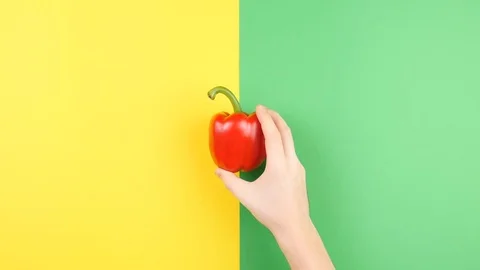 Top view of hand placing sweet red pepper on two colored background Stock Footage 84097903