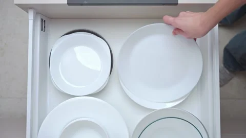 Top view of hand pulling open kitchen drawer with stacked white plates inside Stock Footage 327986142