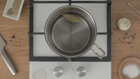 Top view of hand puts black pepper in pot with water leaf on gas stove Vidéo 114085538