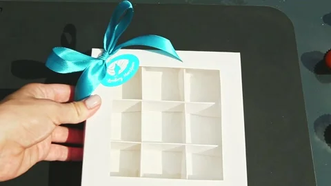 Top view on hand puts empty white gift box with square sections and takes off Stock Footage 130259063