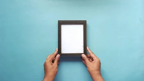 Top view of hand putting empty frame on table Stock Footage 242898762