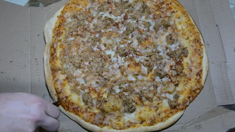 Top view of a hand slicing a tuna pizza with a cutter on a carton box Stock-Footage 123935446