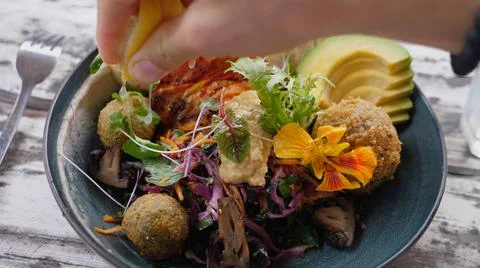 Top view of hand squeezing lemon on healthy delicious vegan Buddha bowl Stock Photos