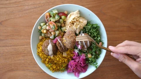 Top view of hand tacking falafel out of oriental style Buddha bowl served on a Stock Footage 148544407