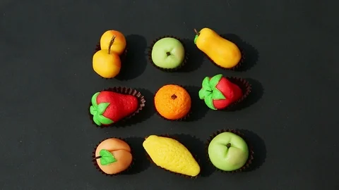 Top view on hand takes away fruit shaped marzipan candy from assortment Stock Footage 124915855
