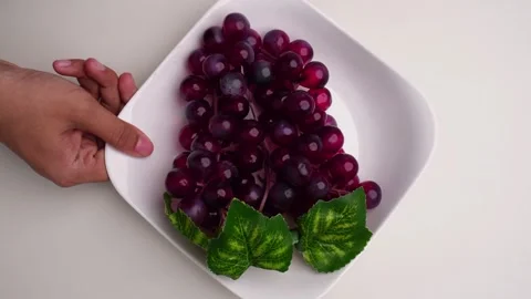 Top view hand taking out and putting down a plate of red grapes 库存影片 274243900