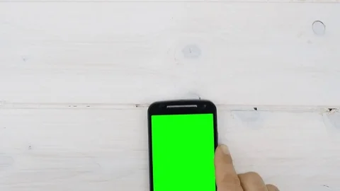 Top view hand tapping on green screen smartphone on desk Stock Footage 71933219