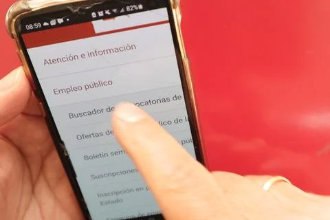 Top view of hand touching smartphone on Spain government Empleos Publicos site Stock Photos
