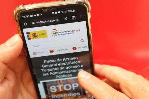 Top view of hand touching smartphone on Spain government site against red color Stock Photos