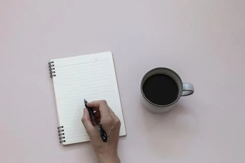 Top view of hand writing on empty notebook near cup of black coffee Stock Photos