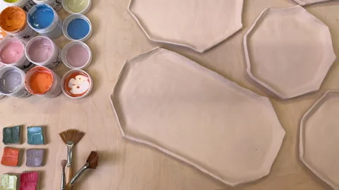 Top view of handmade clay plates and glaze jars ready for painting 스톡 동영상 306278331