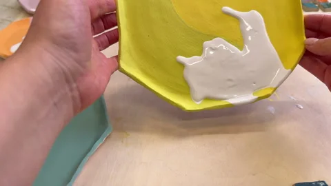 Top view of handmade clay plates covered with colored glazes and glaze jars, rea Stock-Footage 306278525