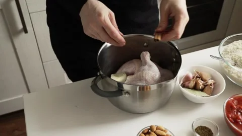 Top view of hands adding a cinnamon stick to raw chicken in pot with bay le.. Vídeos de archivo 332791606