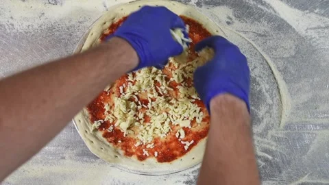 Top view hands are sprinkling fresh grated cheese on pizza dough Stock Footage 156454021