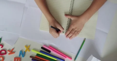 Top view the hands of a child from an elementary school who writes the alphabet Stock Footage 282094935
