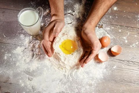 The top view, the hands of the cook, the egg knocked into the flour, a glass  Stock Photos