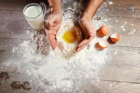 The top view, the hands of the cook, the egg knocked into the flour, a glass  Stock Photos