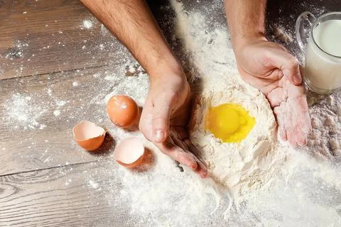 The top view, the hands of the cook, the egg knocked into the flour, a glass  Stock Photos