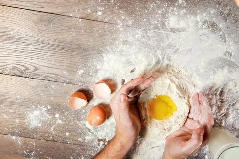 The top view, the hands of the cook, the egg knocked into the flour, a glass  Stock Photos