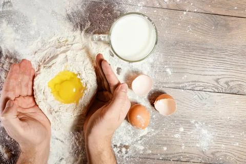The top view, the hands of the cook, the egg knocked into the flour, a glass  Stock Photos