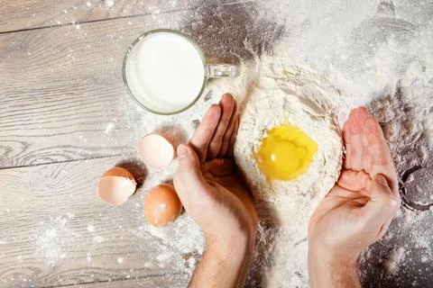 The top view, the hands of the cook, the egg knocked into the flour, a glass  Stock Photos
