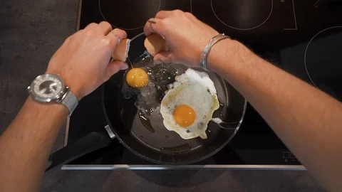Top view of hands cracking open two eggs over a pan, 4K Stock Footage 129615193