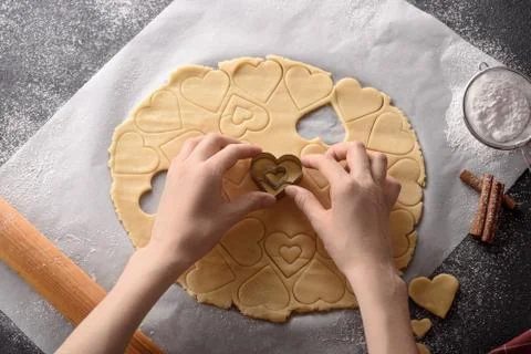 Top view hands cut out hearts from cookie dough on kitchen gray table Stock Photos