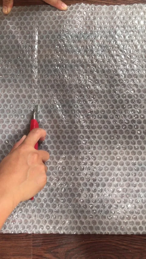 Top View of Hands Cutting Bubble Wrap Plastic with cutter 4K Stock Footage 337720623