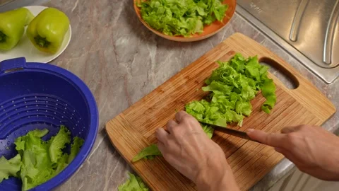 Top view of hands cutting leafy lettuce into bite-sized pieces on a cutting Video stock 316691981