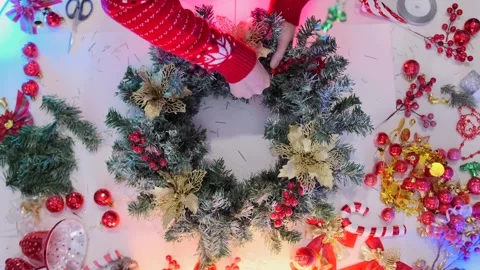 Top view of hands decorating a Christmas wreath with golden flowers and red Stock Footage 318203649